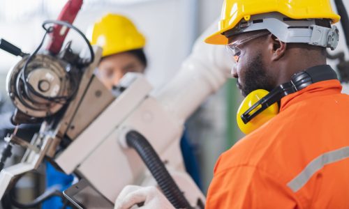 engineer cooperation male and female technician maintenance control relay robot arm system welding with tablet laptop to control quality operate process work heavy industry 4.0 manufacturing factory